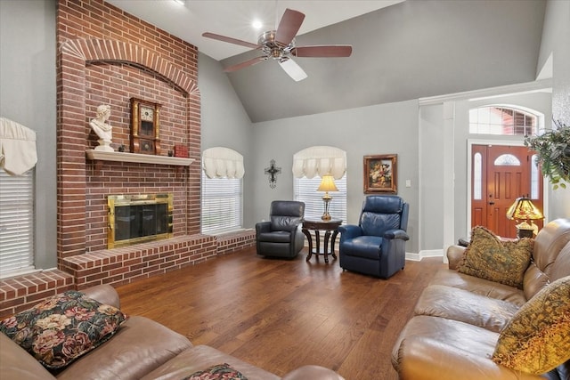 living room with a fireplace, hardwood / wood-style flooring, ceiling fan, vaulted ceiling, and brick wall