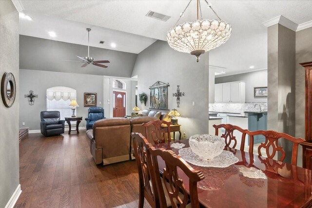 dining room featuring ceiling fan with notable chandelier, dark hardwood / wood-style flooring, crown molding, vaulted ceiling, and sink