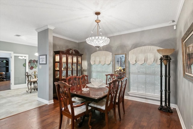 dining area featuring hardwood / wood-style floors, ornamental molding, and a notable chandelier