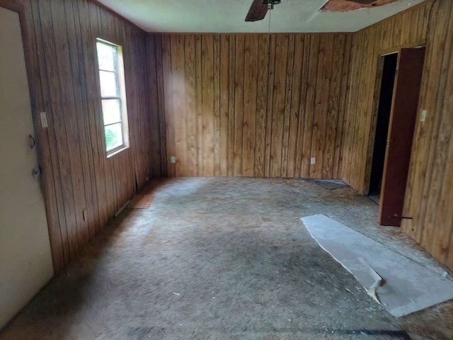 spare room with ceiling fan and wooden walls