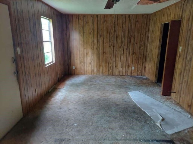 spare room with ceiling fan and wood walls