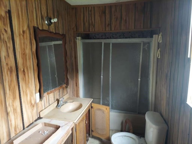 bathroom with enclosed tub / shower combo, vanity, and wooden walls