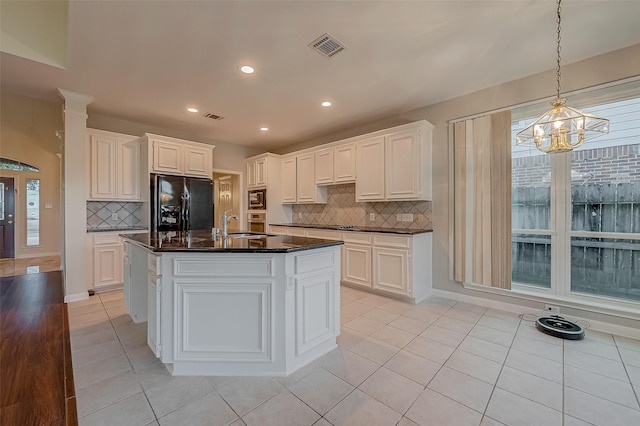 kitchen with light tile patterned floors, a center island with sink, black refrigerator with ice dispenser, and white cabinetry