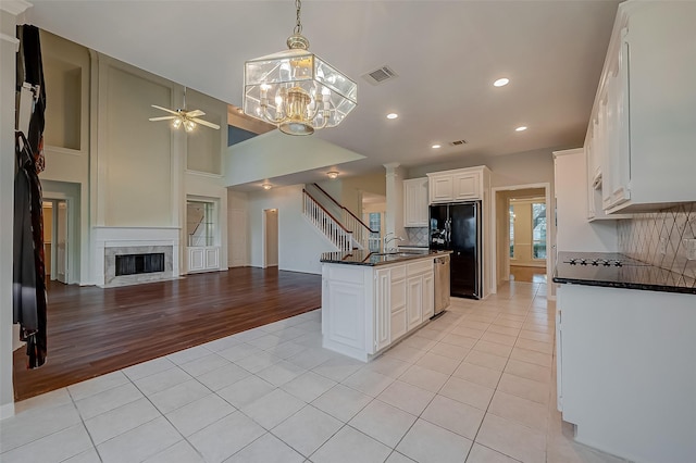 kitchen featuring black fridge, backsplash, white cabinetry, and light tile patterned flooring