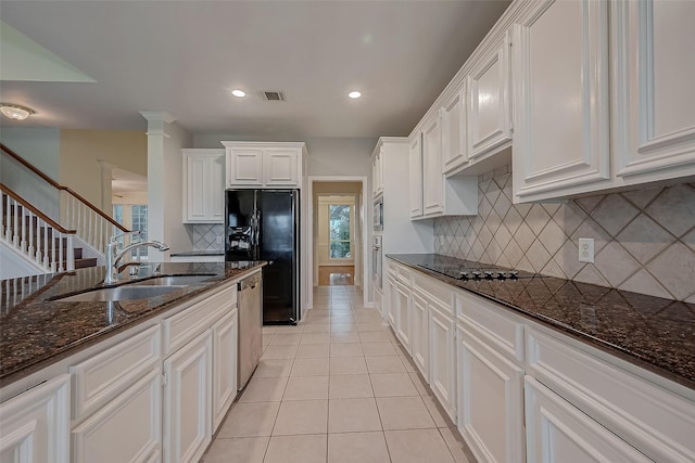 kitchen with dark stone countertops, white cabinetry, sink, and black appliances