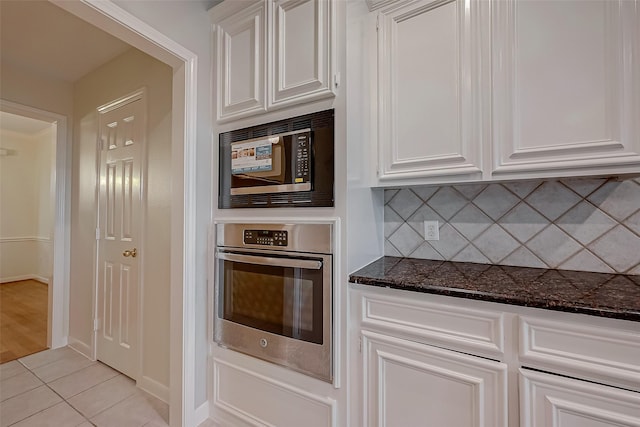 kitchen with oven, white cabinetry, built in microwave, and light tile patterned floors