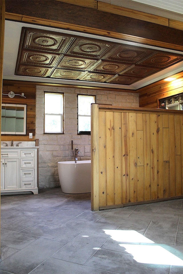 bathroom featuring tile patterned flooring, a bathing tub, wooden walls, and vanity