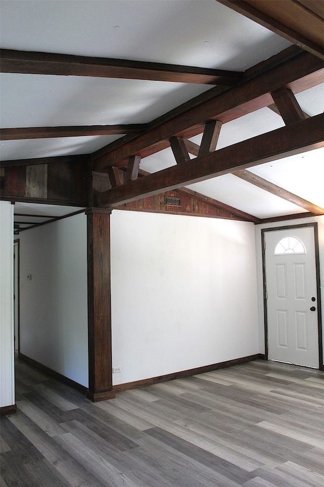 unfurnished living room with lofted ceiling with beams, hardwood / wood-style flooring, and wooden walls