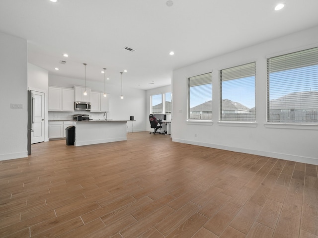 unfurnished living room with sink and light hardwood / wood-style flooring