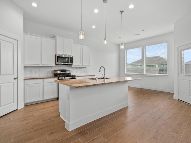 kitchen with a kitchen island with sink, sink, stainless steel appliances, and white cabinets