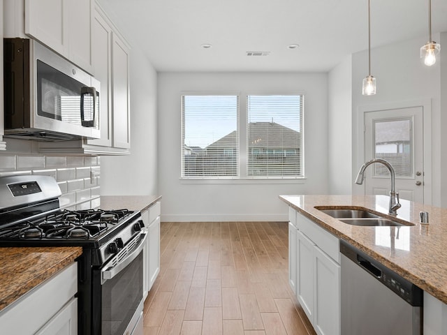 kitchen with stainless steel appliances, white cabinetry, tasteful backsplash, sink, and light stone counters