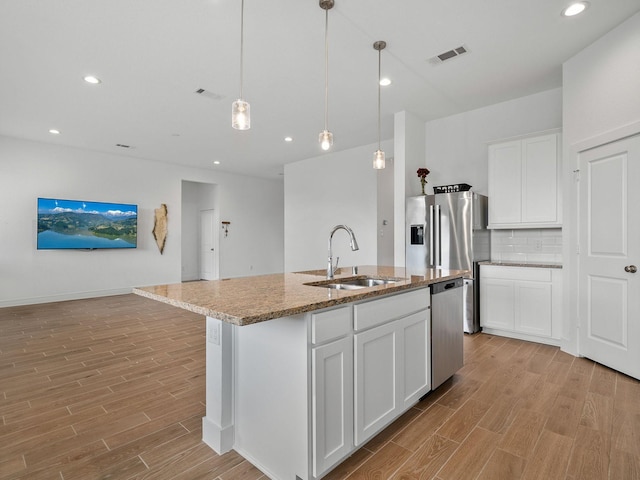 kitchen featuring sink, white cabinetry, hanging light fixtures, dishwasher, and an island with sink