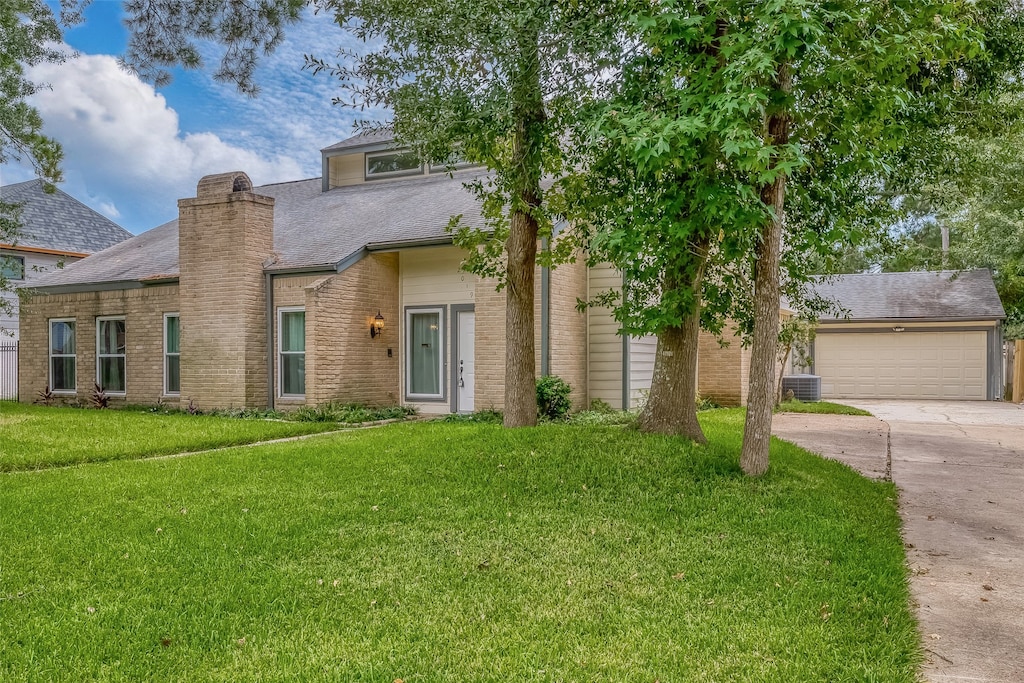 view of front facade featuring a garage, central AC, and a front yard