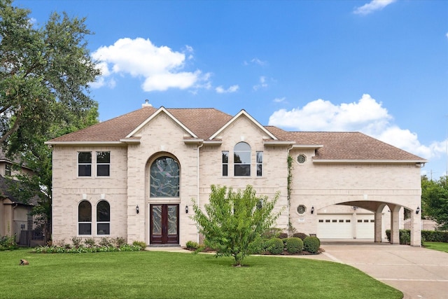 view of front facade with brick siding, driveway, french doors, a chimney, and a front yard