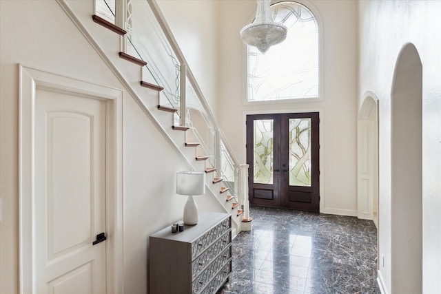 tiled entrance foyer with a towering ceiling and french doors