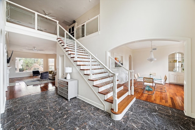 stairs featuring ceiling fan, hardwood / wood-style floors, and crown molding