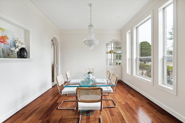 dining area with hardwood / wood-style floors, ornamental molding, and a notable chandelier