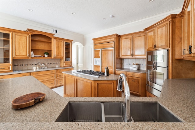 kitchen with paneled built in refrigerator, sink, stainless steel gas stovetop, and backsplash