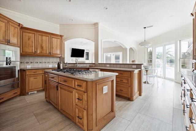 kitchen featuring tasteful backsplash, pendant lighting, stainless steel appliances, a center island, and light tile patterned floors