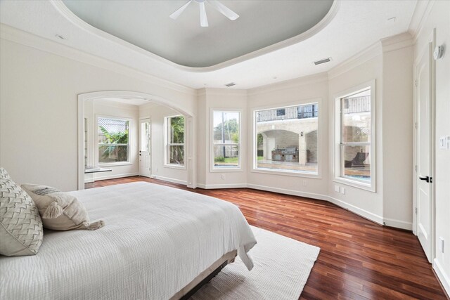 bedroom featuring ceiling fan, wood-type flooring, ornamental molding, and a tray ceiling