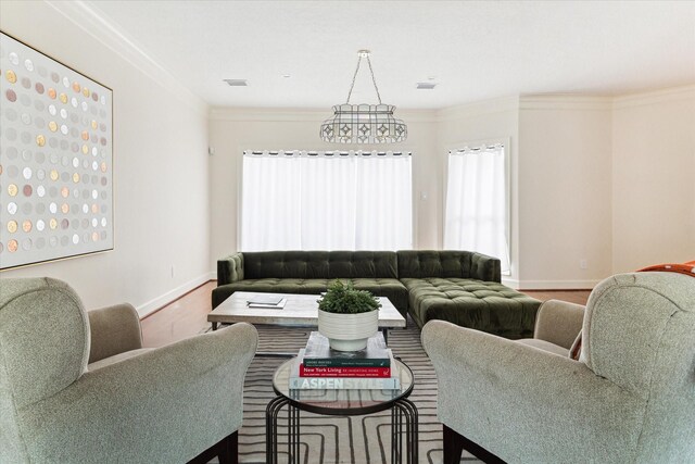 living room featuring an inviting chandelier, ornamental molding, and hardwood / wood-style flooring