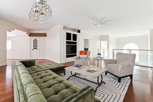 living room with wood-type flooring, ceiling fan with notable chandelier, and crown molding