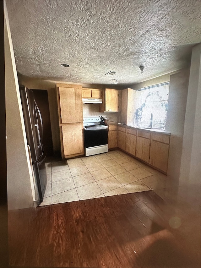 kitchen featuring a textured ceiling, electric stove, black refrigerator, and light hardwood / wood-style floors