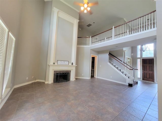 unfurnished living room with a tiled fireplace, tile patterned flooring, ceiling fan, and a high ceiling