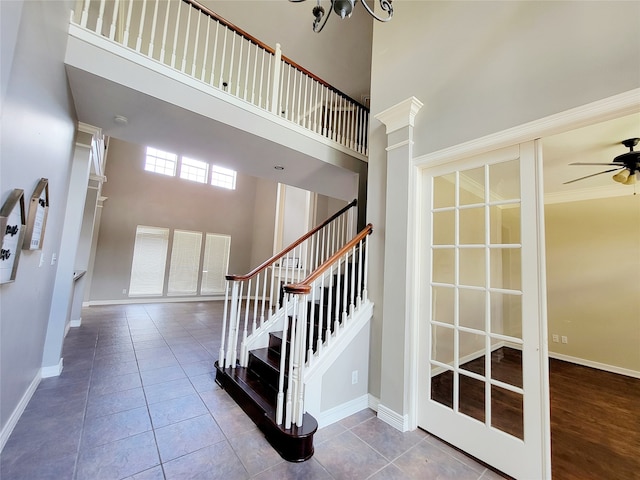 stairway with ceiling fan with notable chandelier, hardwood / wood-style floors, ornate columns, a high ceiling, and ornamental molding