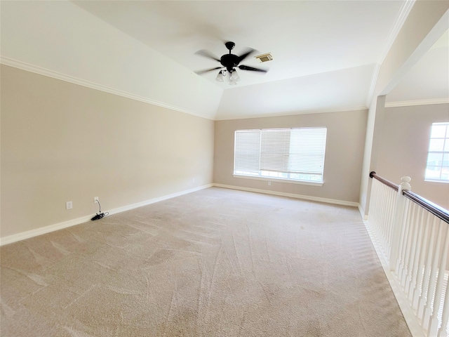 carpeted empty room with vaulted ceiling, crown molding, and ceiling fan