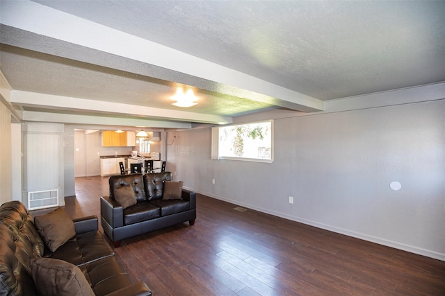 living room with beamed ceiling, dark hardwood / wood-style flooring, and a textured ceiling