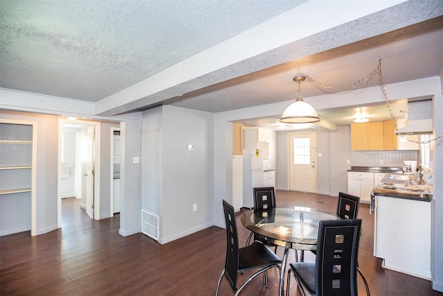 dining space with sink, dark hardwood / wood-style flooring, and a textured ceiling