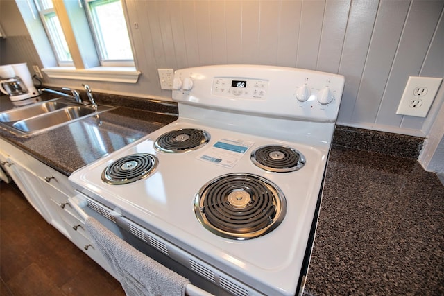 interior details featuring white range with electric stovetop, sink, dark tile patterned floors, and dark stone counters