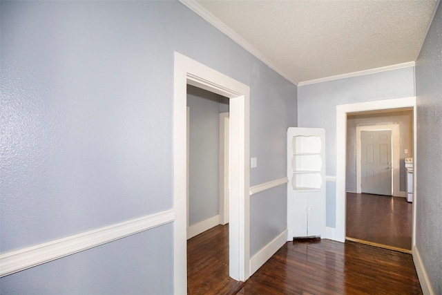 corridor with a textured ceiling, crown molding, and dark wood-type flooring