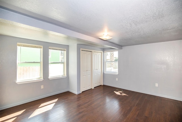 spare room featuring dark wood-type flooring and a textured ceiling