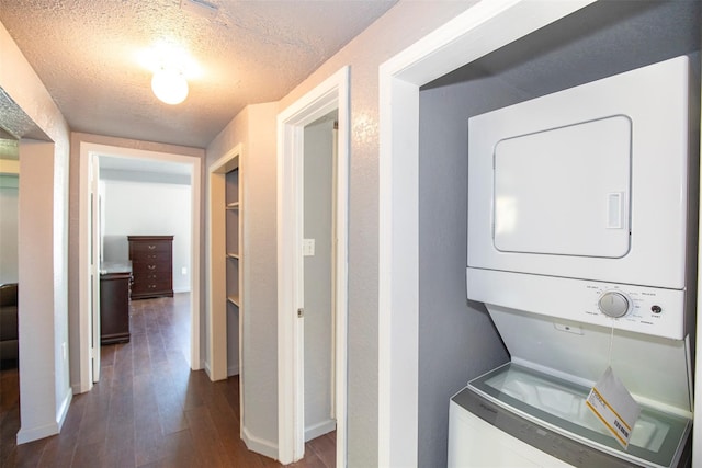 laundry area with wood-type flooring, stacked washer / dryer, and a textured ceiling