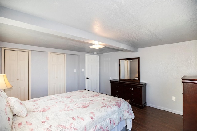 bedroom with a textured ceiling, multiple closets, and dark hardwood / wood-style flooring