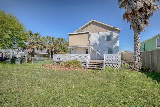 rear view of property with a wooden deck and a lawn