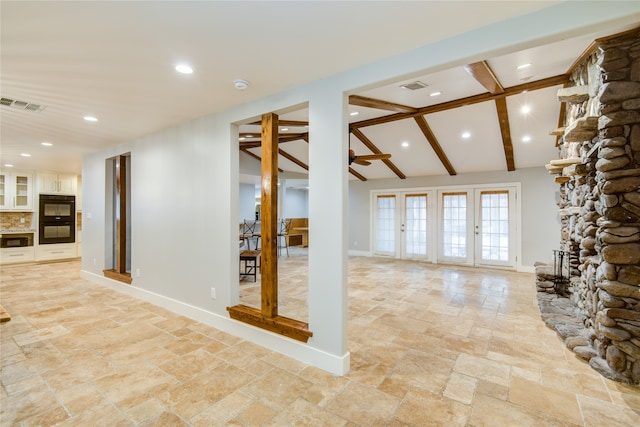 interior space with french doors, ceiling fan, vaulted ceiling with beams, and a fireplace