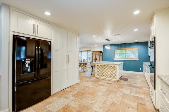 kitchen with pendant lighting, white cabinetry, a kitchen island, and black refrigerator with ice dispenser