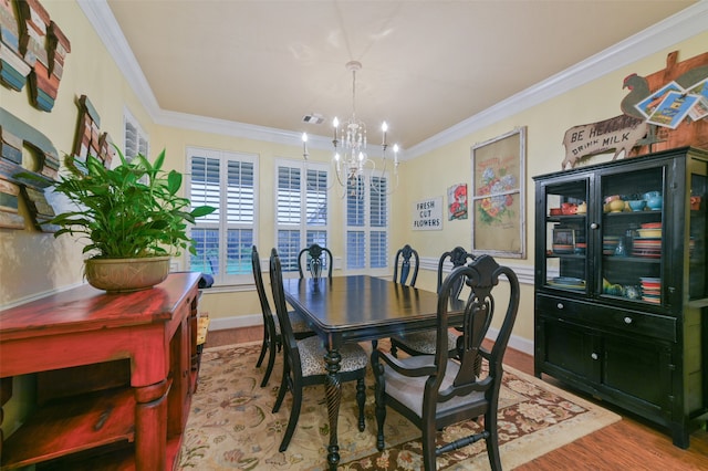 dining space featuring crown molding, hardwood / wood-style flooring, and a chandelier