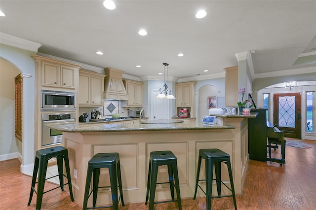 kitchen with custom exhaust hood, stainless steel appliances, crown molding, and hardwood / wood-style flooring