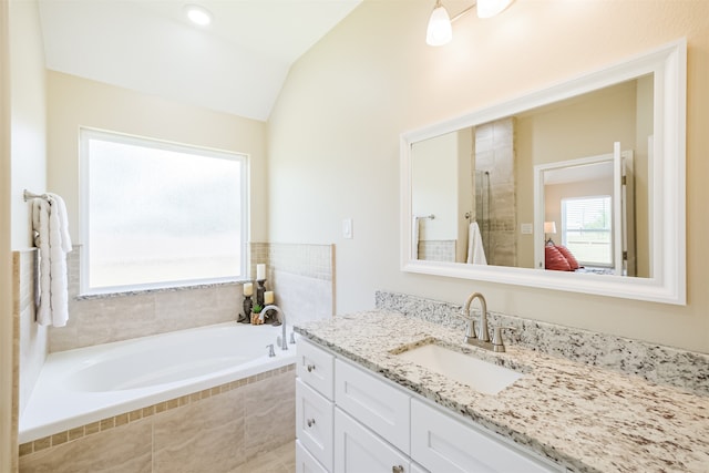 bathroom featuring a relaxing tiled tub, vanity, and lofted ceiling