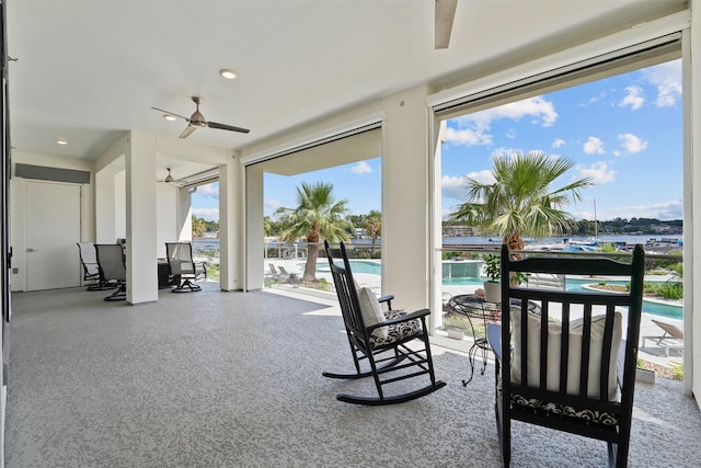 interior space with ceiling fan, a wealth of natural light, and a water view