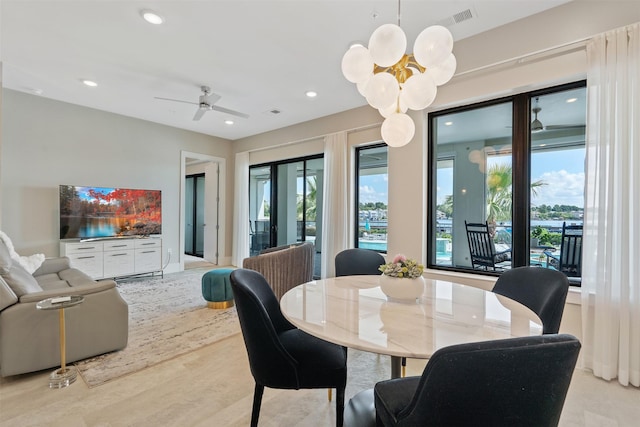 dining area with ceiling fan with notable chandelier and light hardwood / wood-style flooring