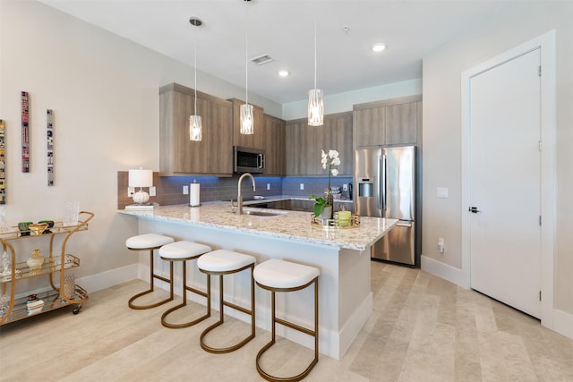 kitchen with stainless steel appliances, sink, kitchen peninsula, backsplash, and hanging light fixtures