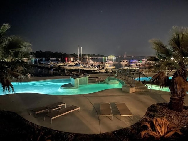 pool at night featuring a patio area