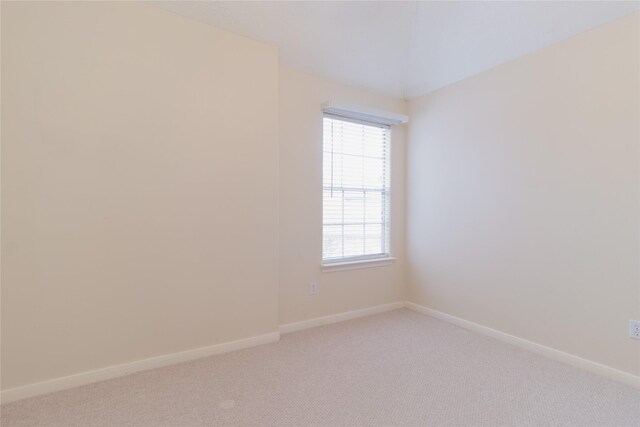 spare room with baseboards and light carpet