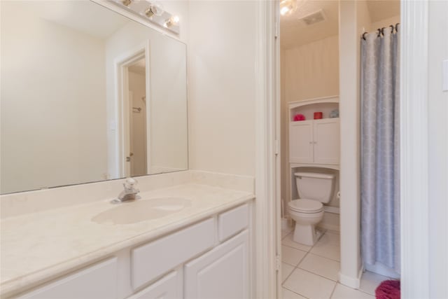 bathroom with toilet, vanity, and tile patterned flooring