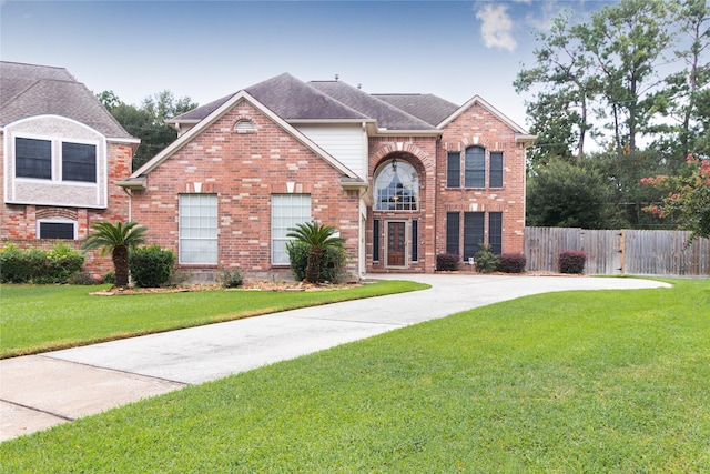 traditional-style home with brick siding, fence, and a front yard
